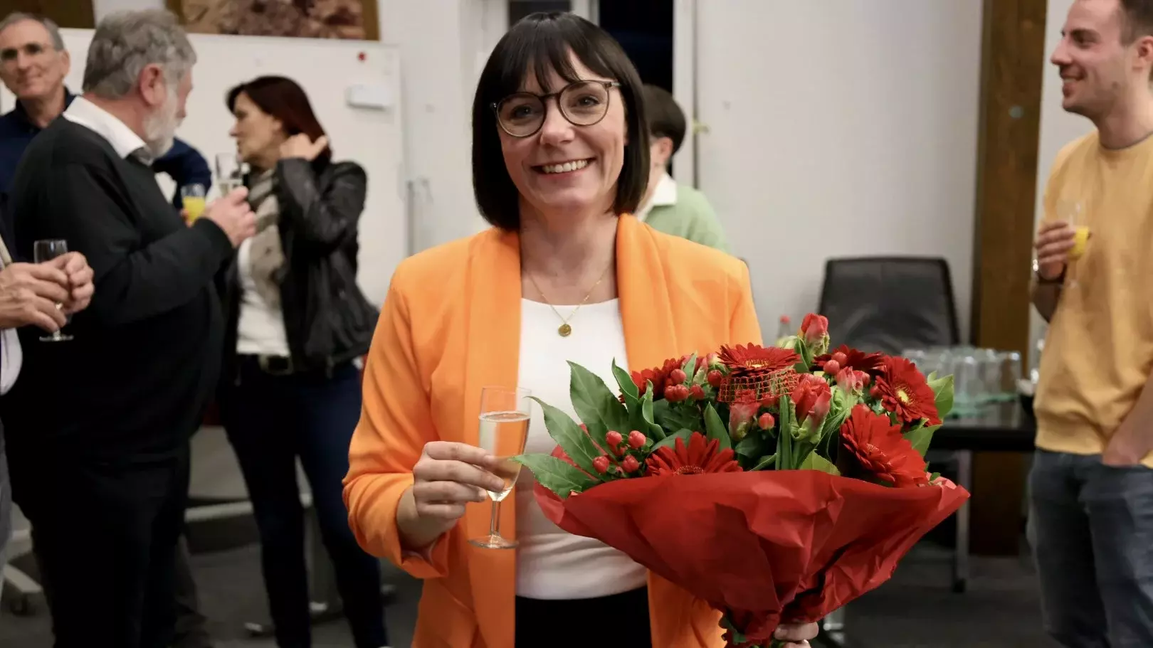 Sarah Höfler mit Blumenstrauß und Sektglas im Sitzungssaal