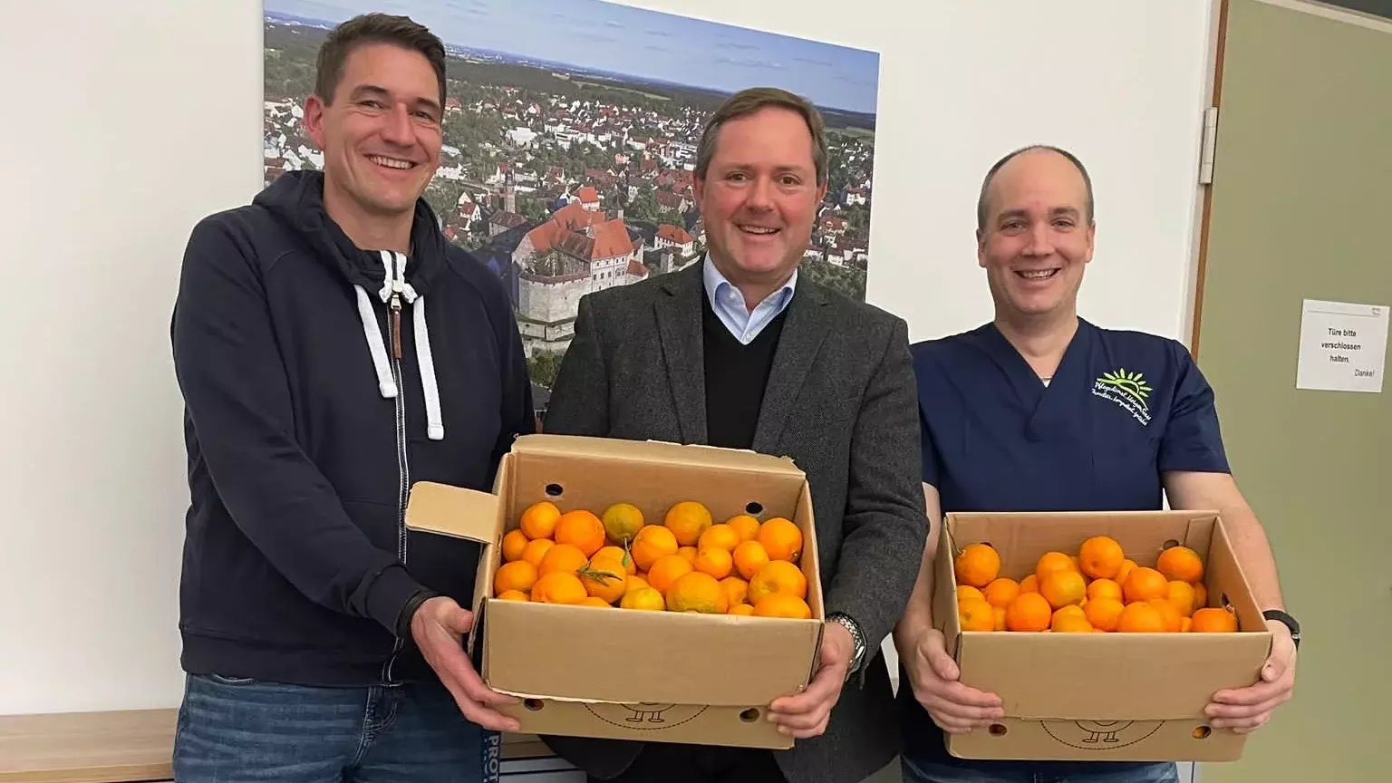 Benjamin Kulling übergibt Orangen an Bürgermeister Bernd Obst und Geschäftsführer Johannes Kreß